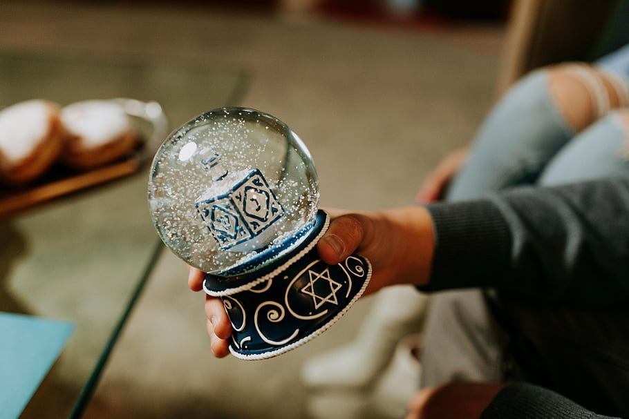 hanukkah snow globe dreidel star of david hand holding festive ornament holiday decoration winter scene cultural symbol traditional gift snow globe